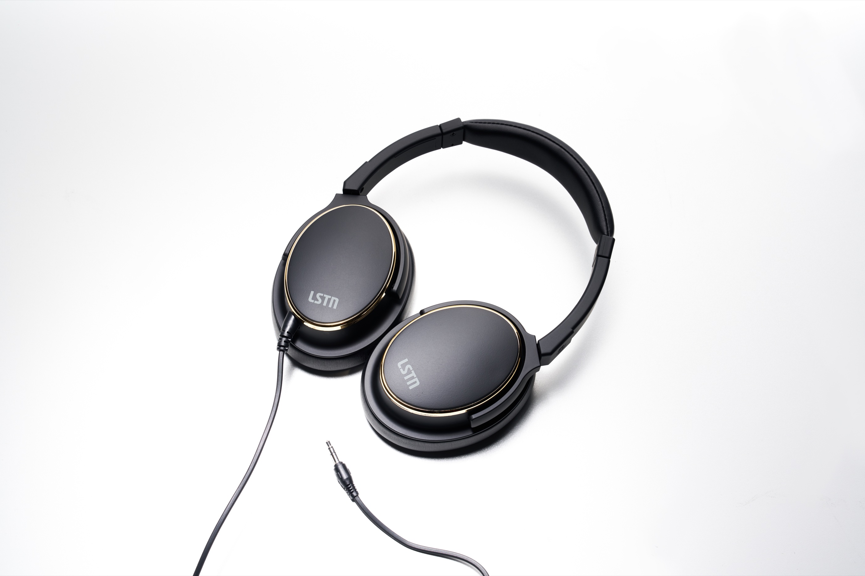 The headphones laid flat on white, showing both earcups and the detachable 3.5 mm single-pin cable and connector specified for airline service.